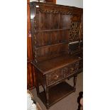 An 18th century style oak dresser, carved plate rack above base with twin moulded drawers, pot-board
