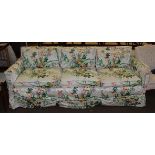 A three-seater sofa, upholstered in floral fabric