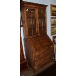 A Georgian style oak bureau bookcase, twin glazed doors above four flap fitted interior, two short