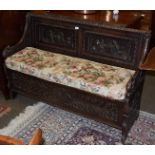 A 19th century oak box settle, with heavily carved panels and hinged seat, 135cm wide