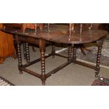 A oak drop leaf dining table with turned supports