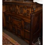 A 20th century oak court cupboard, heavily carved, twin central cupboards with profile roundels,