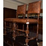 A pair of oak chairs with studded and embossed leather work decorated with leaves and scrolls