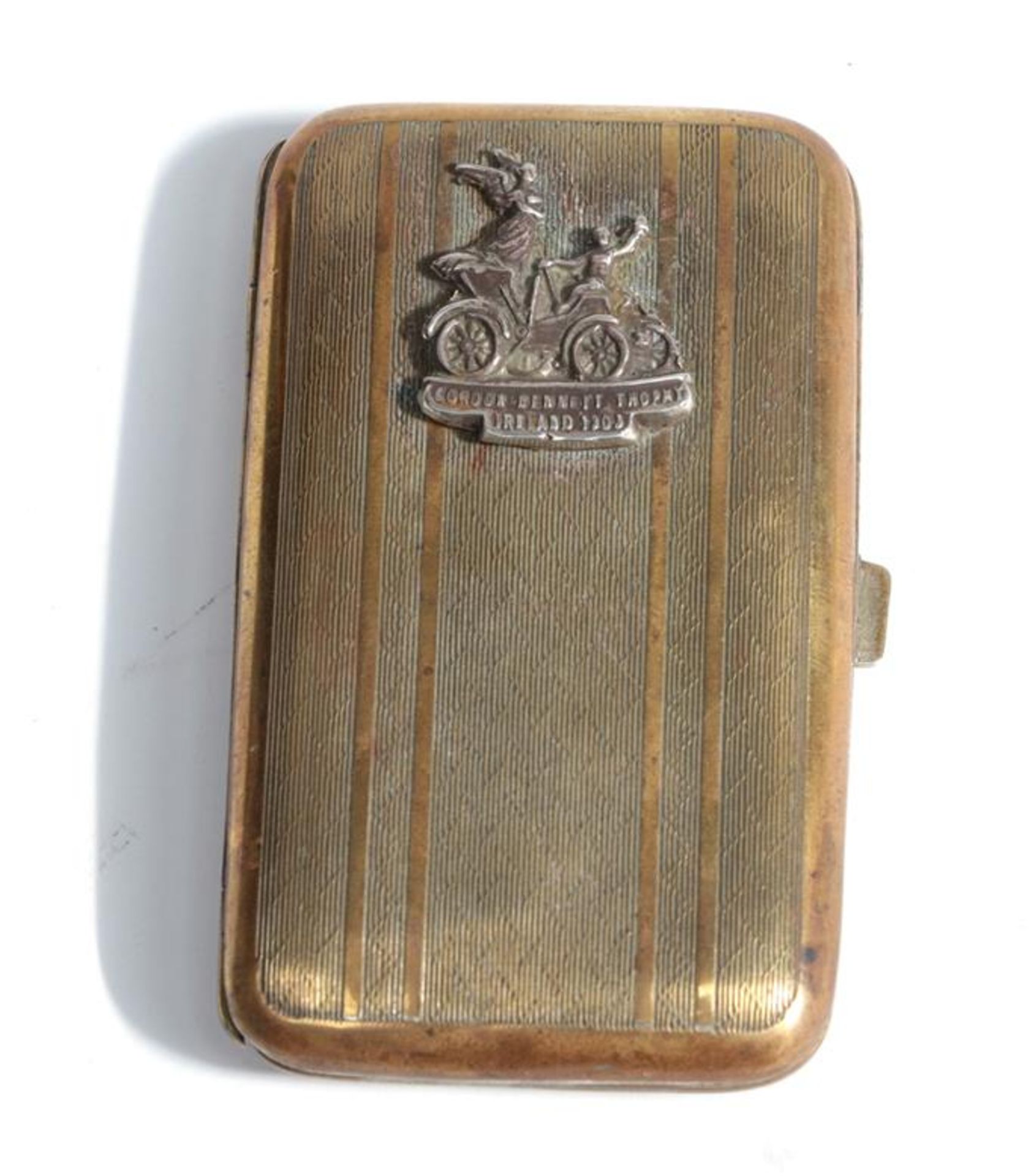 A Brass Cigarette Case, with engine turned decoration and surmounted by a badge engraved Gordon
