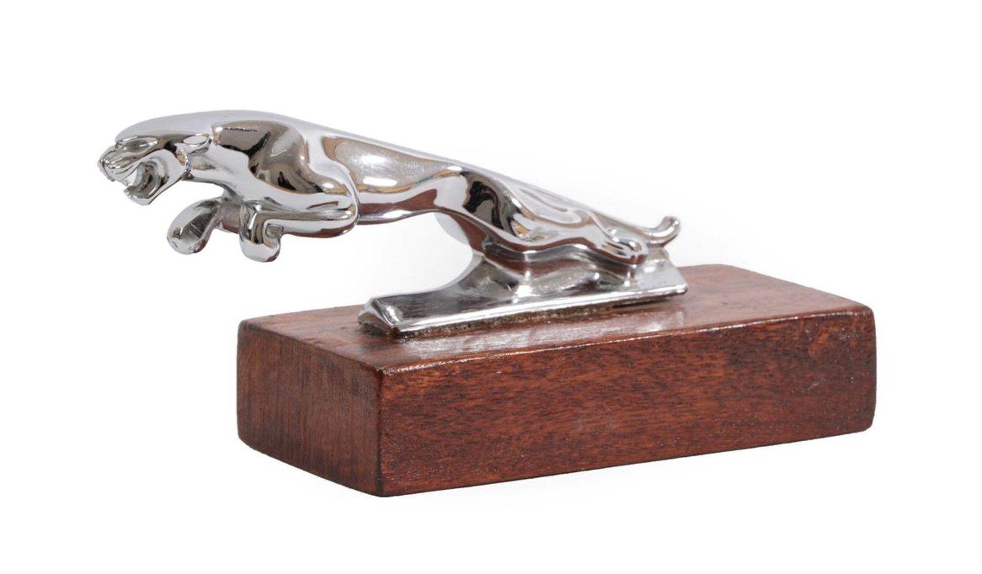 A Chrome Car Mascot as a Leaping Jaguar, mounted on a stained wood rectangular base, 13cm long