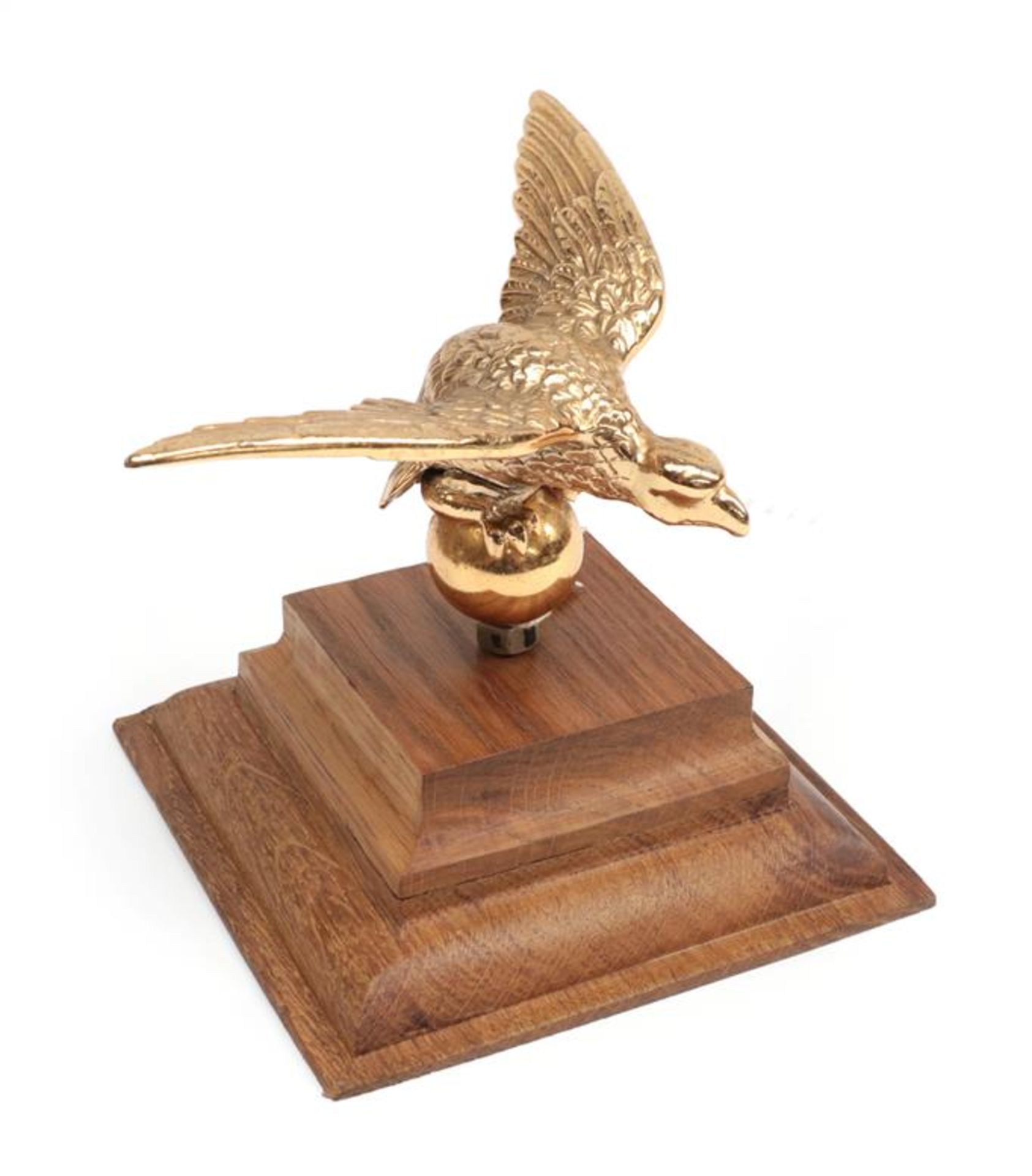 A Gilded Metal Car Mascot as a Winged Eagle, possibly from an Alvis, mounted on a graduated oak