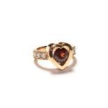 An heart shaped ring, with a red synthetic stone centrally and diamond set shoulders, stamped '