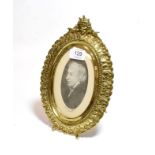 A Victorian gilt brass easel-backed photograph frame, cast with leaves and surmounted by a female