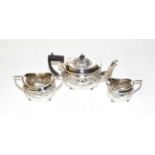 A silver three-piece tea service, Birmingham marks, with ornate repousse decoration of scrolls and