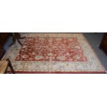 An Afgan Ziegler rug, the brick red field with all over design of flowers and vines enclosed by