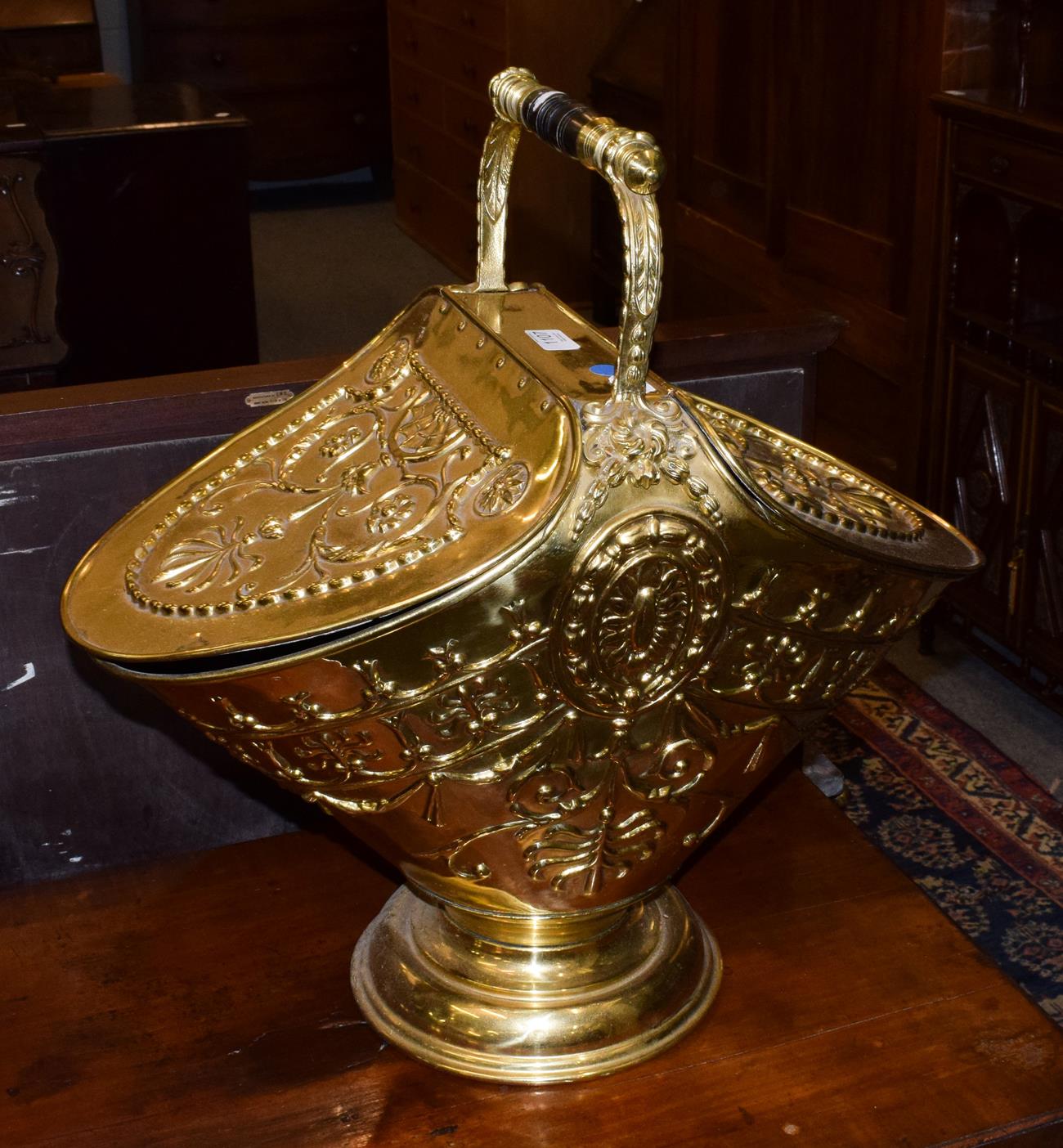 A Victorian style embossed brass coal hod, with turned handle above two hinged lids decorated with