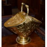 A Victorian style embossed brass coal hod, with turned handle above two hinged lids decorated with