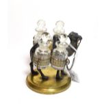 A set of four cut-glass scent bottles on a metal stand cast as a camel and with a round brass