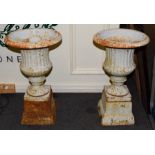 A pair of painted cast iron campana shaped garden urns on pedestals (2)