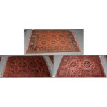 Afghan Turkman rug, the teracotta field of hooked guls, 143cm by 98cm together with two other