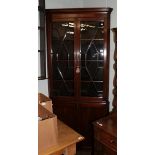 A late George III mahogany floor standing corner cupboard, with a moulded cornice over an astragal