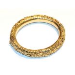 A floral chased hinged bangle, inner measurements 5.8cm by 6.6cm. Clasp indistinctly marked. Gross