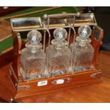 An oak and silver plated three-bottle tantalus (open but no key present)