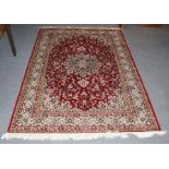 A machine made rug of Oriental design, the blood red floral field centred by medallion framed by