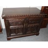A carved oak cupboard, 18th century in part, with two carved cupboard doors, raised on a later base,