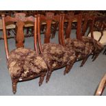 A set of four Victorian carved walnut dining chairs with over-stuffed seats