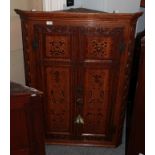 A George III carved oak and marquetry inlaid hanging corner cupboard