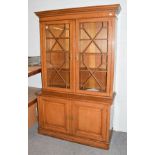 A late Victorian oak bookcase with dentil cornice above astragal glazed doors, the base with two