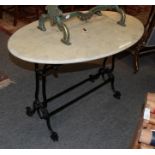 A white marble oval table with black metal scrolled base