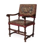 A Late 17th Century Carved Walnut Armchair, covered in close-nailed floral needlework fabric, with