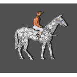 A Horse and Jockey Brooch, the jockey enamelled with a red cap, an orange top, white breeches and