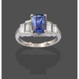A Sapphire and Diamond Five Stone Ring, the central cushion cut sapphire in a white four claw