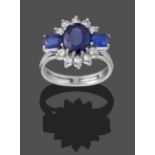 A Sapphire and Diamond Cluster Ring, by Graff, circa 1960, the oval cut sapphire flanked by two