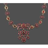 A Garnet and Red Stone Necklace, the central panel formed of a bow motif suspends a scroll motif