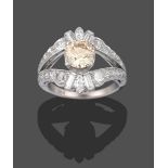 A Diamond Cluster Ring, the central fancy light brown round brilliant cut diamond in a white four