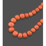 A Coral Bead Necklace, the thirty-nine graduated faceted coral beads terminate to a yellow reeded