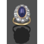 A Sapphire and Diamond Cluster Ring, the oval cabochon sapphire, in a yellow millegrain setting,