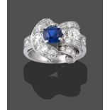 A Sapphire and Diamond Cluster Ring, the central round cut sapphire in a white claw setting,