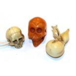 Japanese ivory netsuke as a skull, 2cm high, another as a gourd and an amber skull, 2.3cm high (3) .
