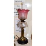 A Victorian oil lamp with cranberry tinted shade, 56cm high . Small chips to the base rim of the