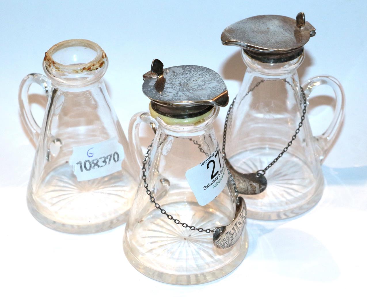 Two whisky noggins with silver lids and spirit labels together with another glass noggin . Spirit