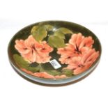 A large Walter Moorcroft bowl, coral hibiscus pattern on green, 23cm diameter . Minor surface