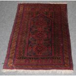 A Baluch Prayer rug, the indigo field of hooked medallions beneath the Mihrab enclosed by multiple