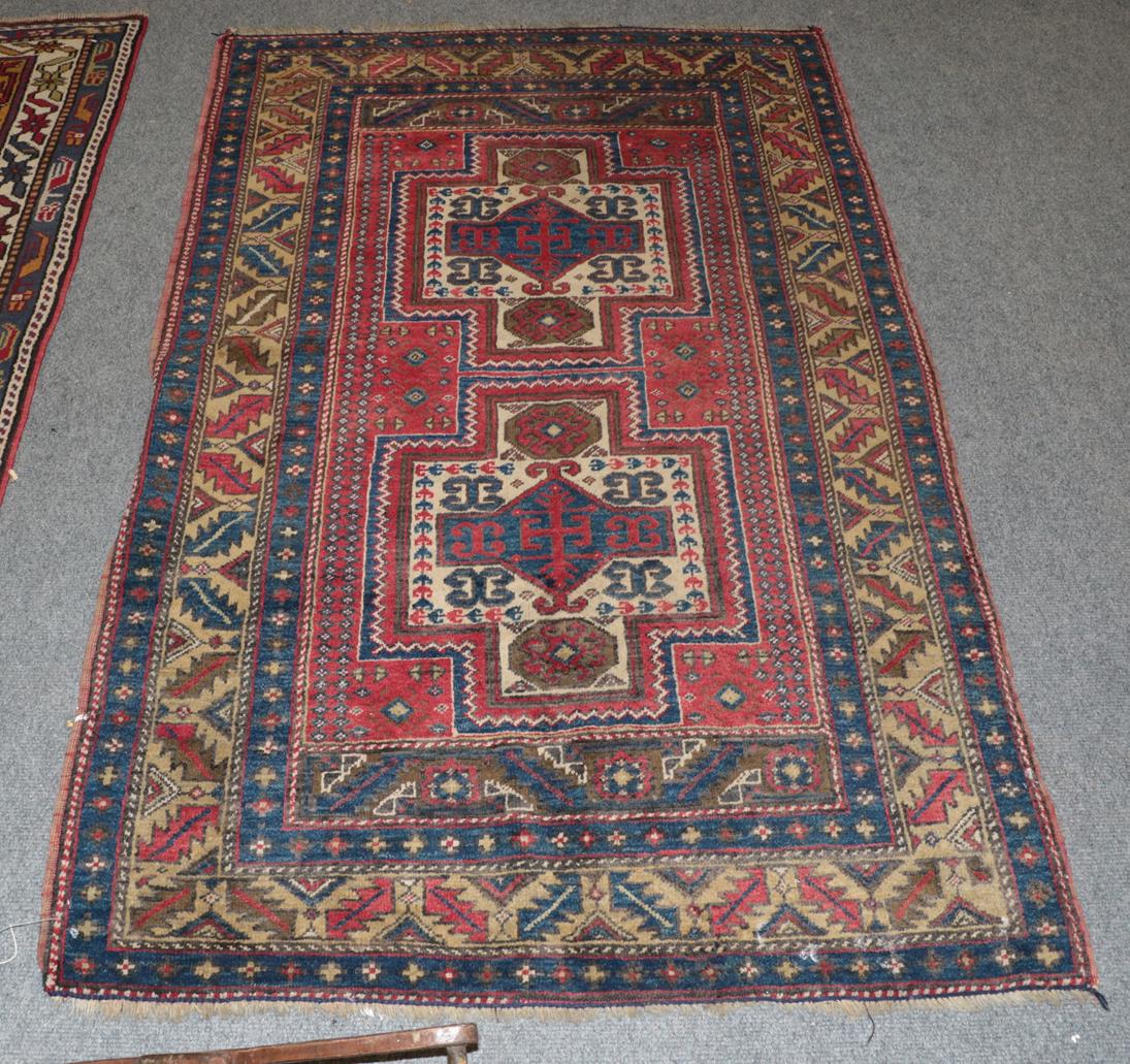 A Kazak Caucasian design rug, The terracotta field with two stepped medallions enclosed by leaf
