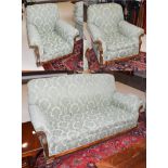 An Early 20th century carved mahogany three piece suite, comprising a three-seater sofa and two