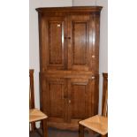 A George III crossbanded and panelled oak standing corner cupboard, 105cm by 204cm high