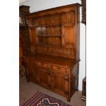 An 18th century style oak dresser with plate rack with an arrangement of shelves, cupboards and