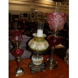 Two Victorian brass oil lamps both with cranberry glass reservoirs and shades, together with a