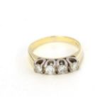 A diamond four stone ring, the round brilliant cut diamonds in white claw settings, to a yellow