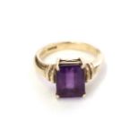 A 9 carat gold amethyst ring, the emerald-cut amethyst in a yellow four claw setting, to a tapered
