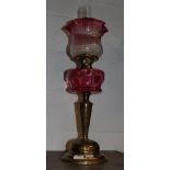 A Victorian brass oil lamp with cranberry glass reservoir and shade